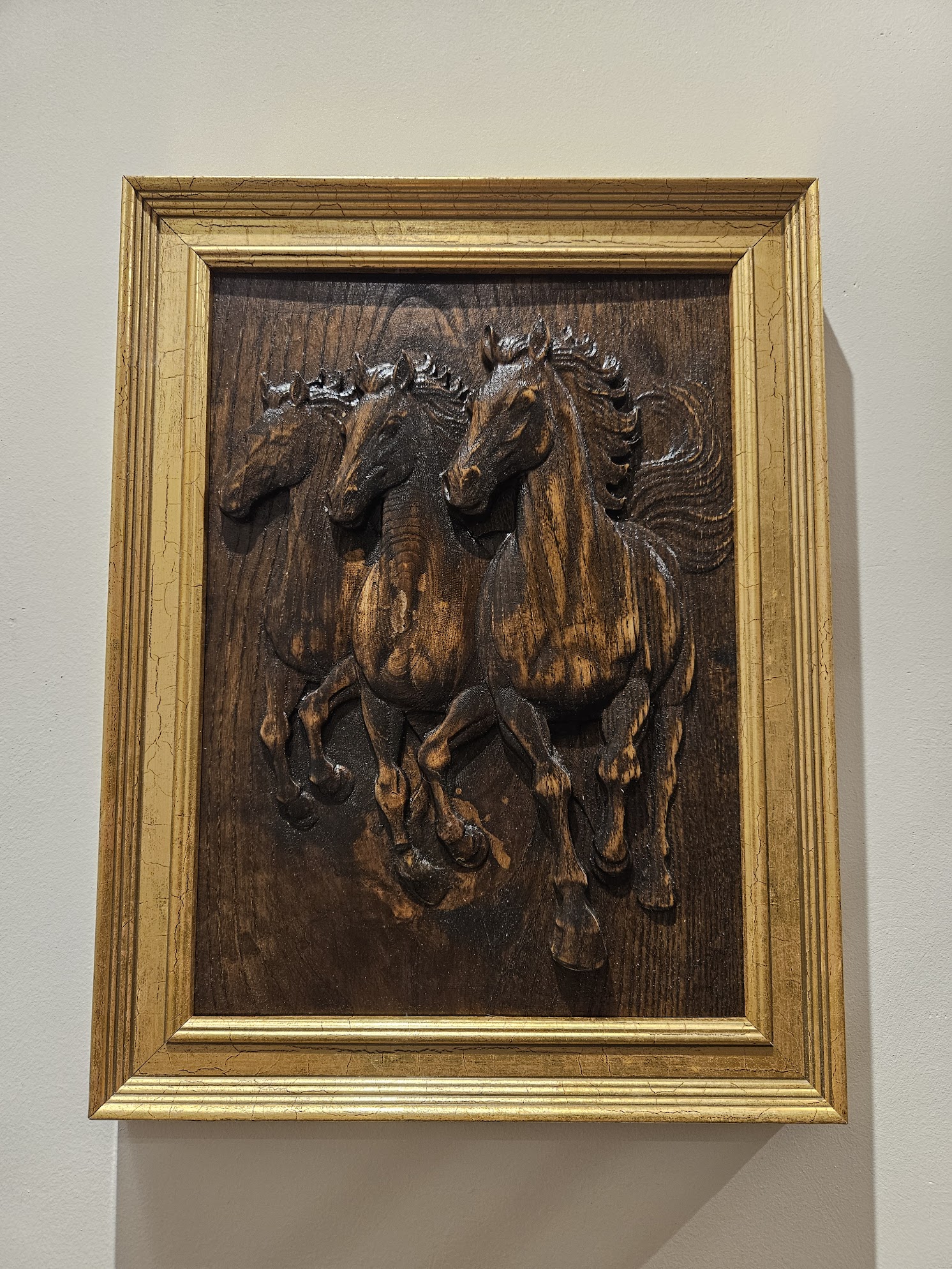 Three horses galloping through a field. Carved from a single block of ash. Danish oil finish. Golden frame.