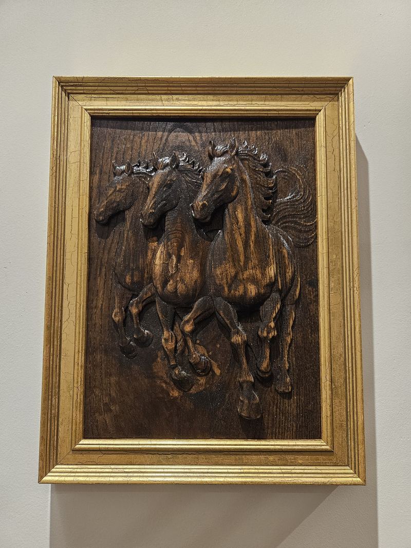 Three horses galloping through a field. Carved from a single block of ash. Danish oil finish. Golden frame.